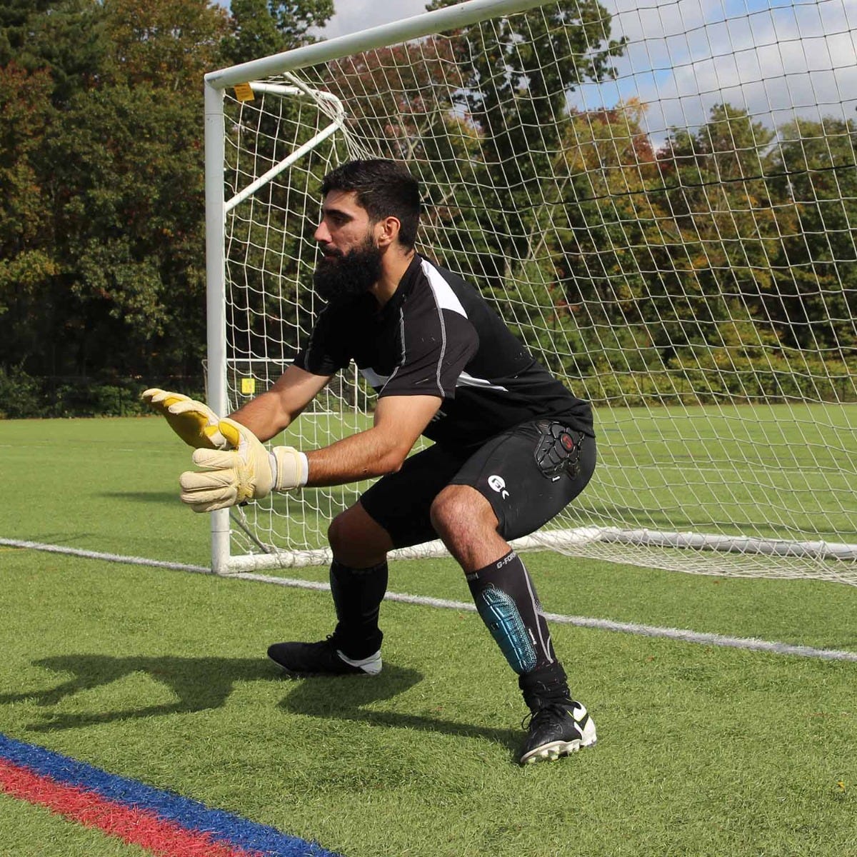 Getry kompresyjne wspomagające skoki i dynamikę Biały piłkarz w niebieskich getrach kompresyjnych skaczący do główki podczas meczu ligowego