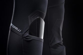 Piłkarz zawodowy w getrach kompresyjnych biegnący po zielonej murawie boiska z ochraniaczami nóg