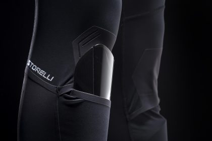 Piłkarz zawodowy w getrach kompresyjnych biegnący po zielonej murawie boiska z ochraniaczami nóg