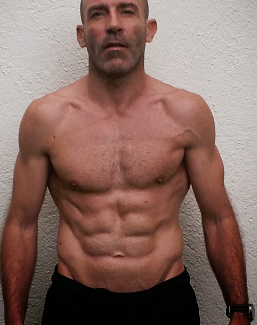 mężczyzna wykonujący dipy na poręczach z tułowiem opuszczonym w dół