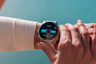 Garmin Fenix 7 i Apple Watch Ultra obok siebie na drewnianym stole z linijką