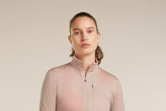 mężczyzna w szarej koszulce merino biegnący po górskim szlaku w słońcu