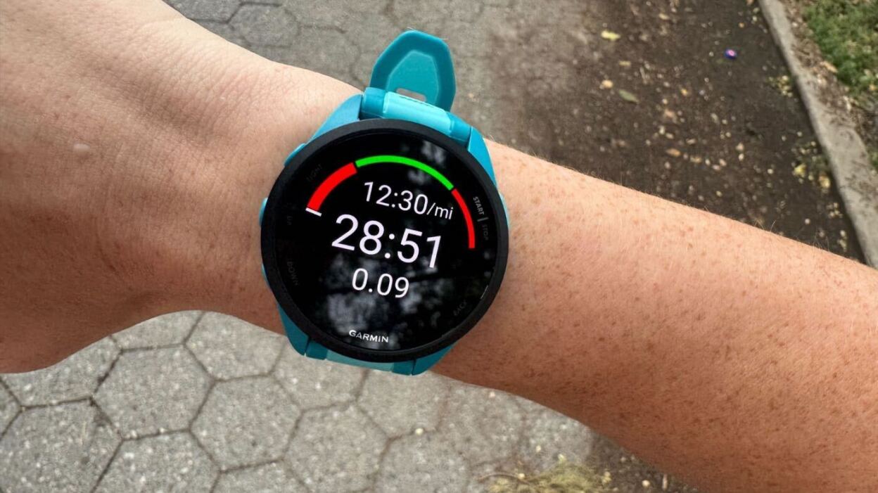 mężczyzna w koszulce biegowej z zegarkiem GPS na nadgarstku biegnący parkiem