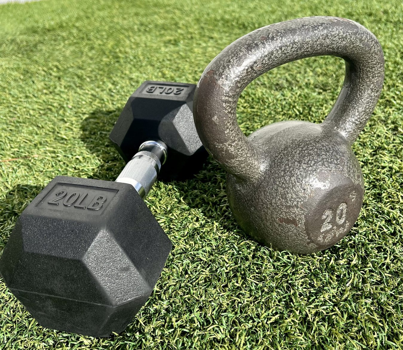 Dobranie obciążenia na trening siłowy osoba porównująca ciężary kettlebell i hantli w rękach